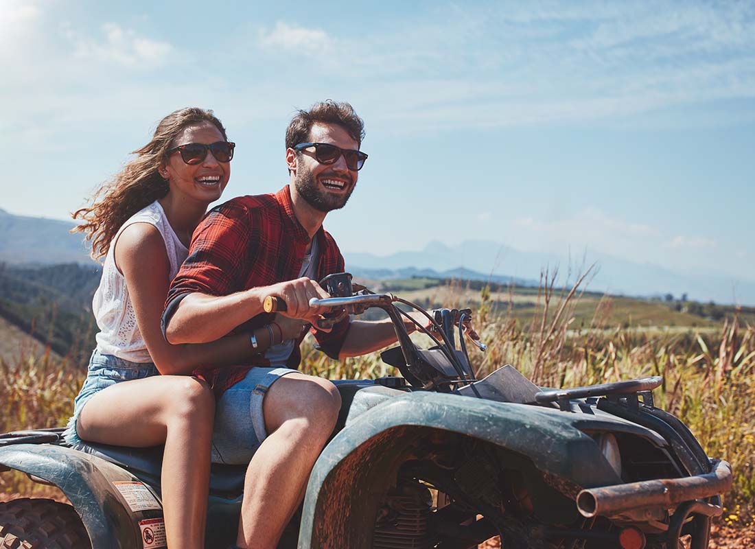 Off-Road-Vehicle-Insurance-Happy-Young-Couple-Riding-ATV-Together-Along-a-Dirt-Road-in-the-Countryside-on-a-Sunny-Day