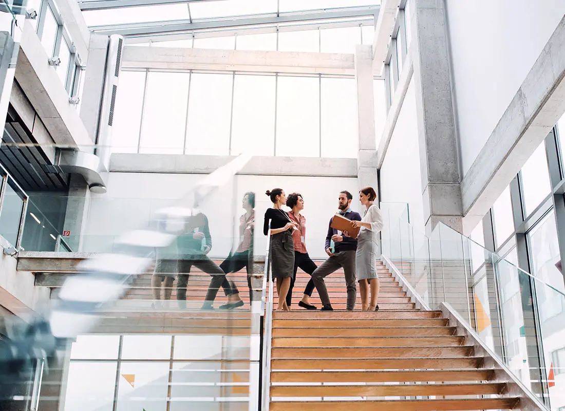 A group of businesspeople standing in a hallway, talking and conversing.